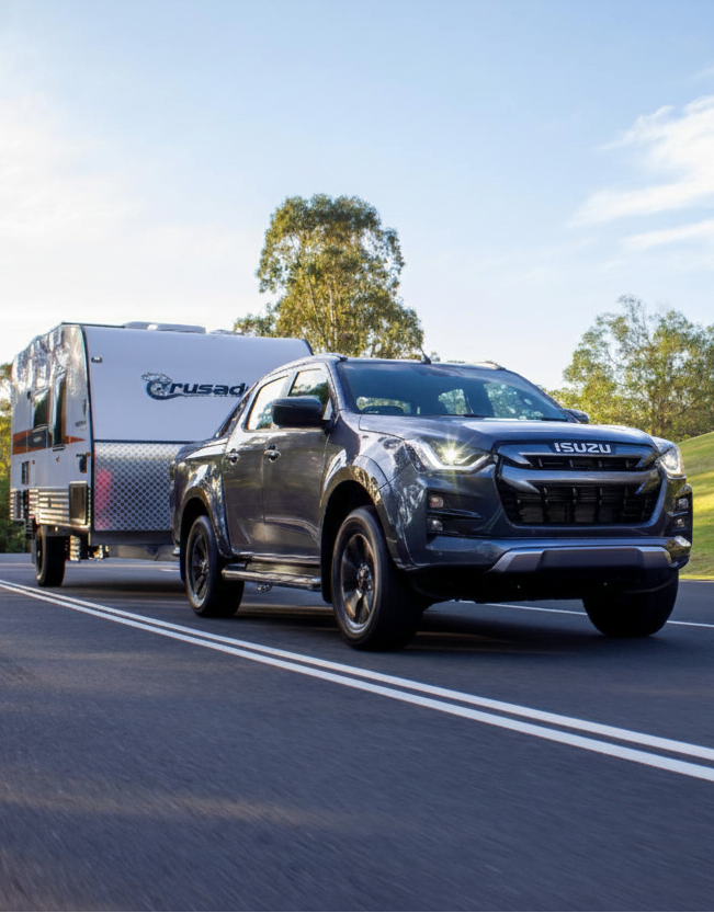 Isuzu Dmax towing a caravan on a road with trees in the background